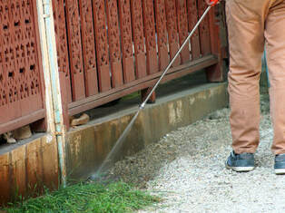 Pest control professional sprays wooden structure for termites on a property in Lehigh Valley.